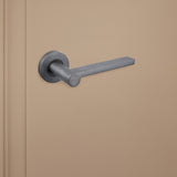 Strakke Gun Metal Caserta binnendeurklink van Lavuzo op beige achtergrond, linkeraanzicht