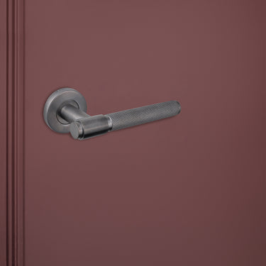Gun Metal PVD gecoate deurkruk Cosenza Knurled met ronde rozet op rode binnendeur, linkeraanzicht