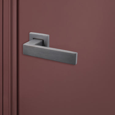Luxe Imperio binnendeurbeslag Gun Metal PVD gecoat met vierkant rozet op donkerrode deur, rechteraanzicht