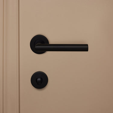 Modern zwart WC-beslag binnenzijde met draaiknop op rond rozet op beige binnendeur, vooraanzicht