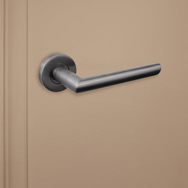 Strakke Gun Metal Ragusa binnendeurklink van Lavuzo op beige achtergrond, linkeraanzicht
