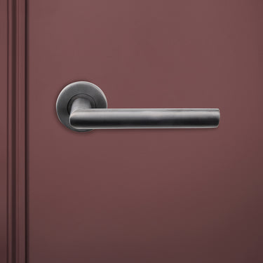 Ragusa PVD gecoate binnendeurkruk Gun Metal met rond rozet op rode deur, vooraanzicht